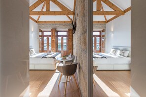 Une chambre avec un grand lit, une petite table et une vue par la fenêtre.