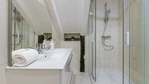 A modern bathroom with a glass-enclosed shower, a white sink, and a mirror. - GuestReady - Miragaia Stone Studio 2T (Porto)