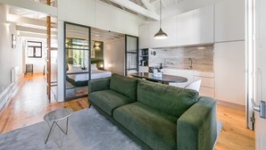 Un intérieur moderne avec un canapé vert, une table à manger et un coin cuisine.