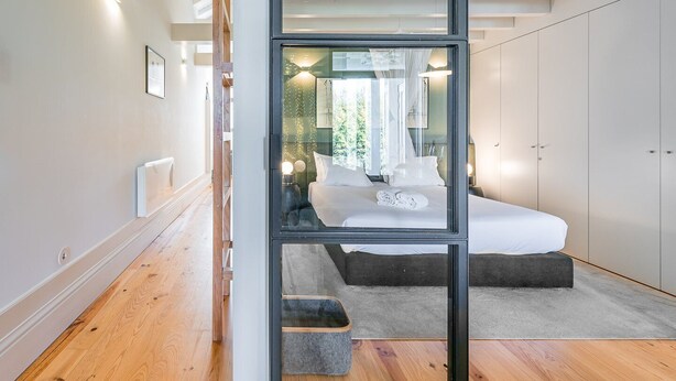 Une chambre moderne avec un grand lit, une cloison en verre et une vue sur un balcon.