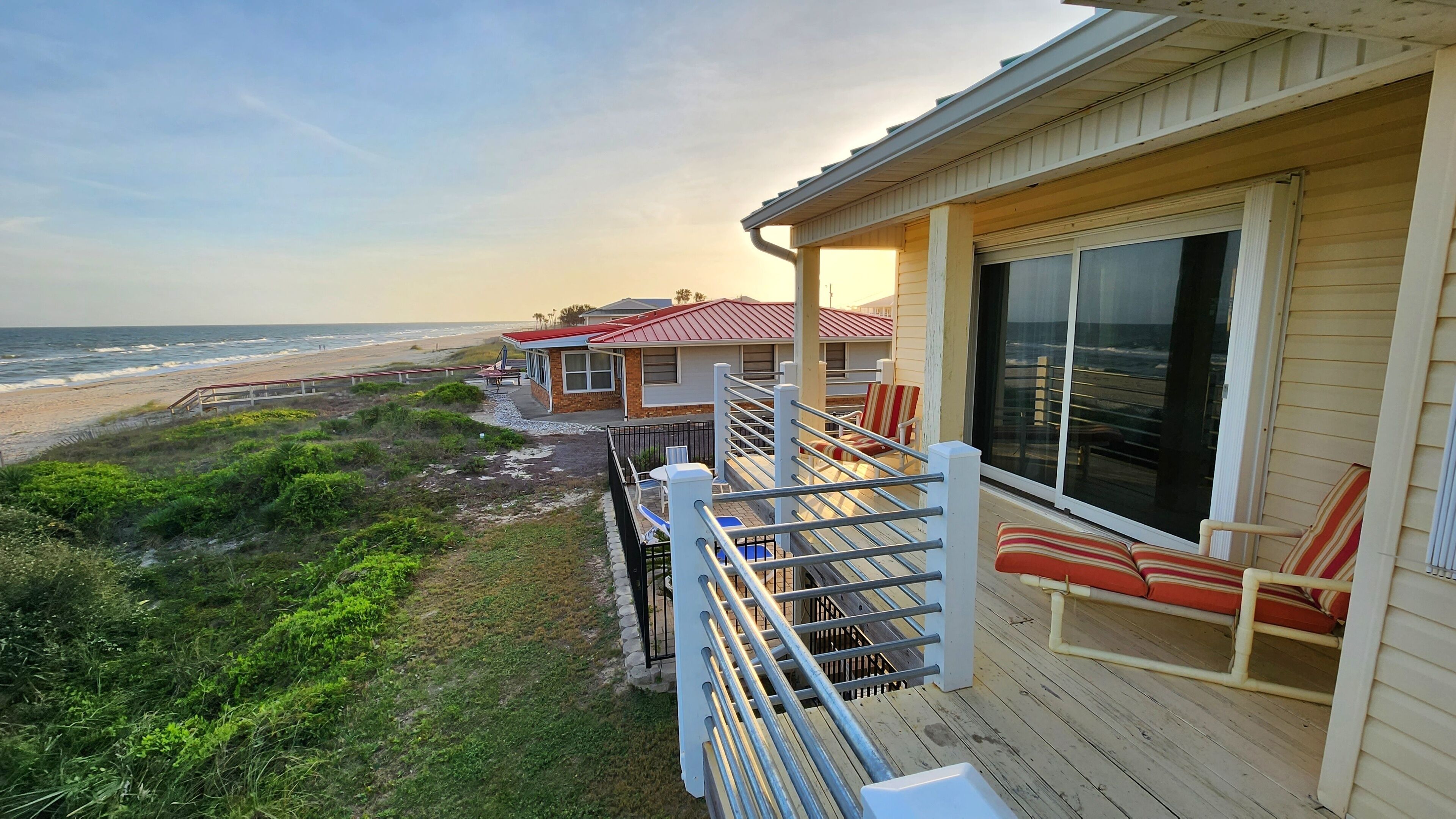Ein Strandgrundstück mit einer Holzterrasse, einer überdachten Veranda und Blick auf den Ozean.