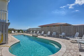 Piscina com espreguiçadeiras e cerca de madeira.