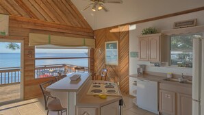 A kitchen with a view of the sea, wooden walls, a ceiling fan, and a small dining area. - Welcome to Bienvenue! (St. George Island)