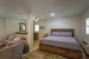 A bedroom with a wooden bed, a sofa, a dresser, and a mirror on the wall. - Easy Beach Access - Newly Updated! (St. George Island)