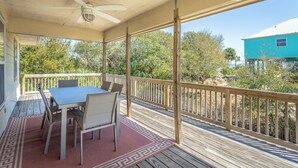 A covered outdoor area with a table and chairs, a ceiling fan, and a view of the surrounding landscape. - Easy Beach Access - Newly Updated! (St. George Island)