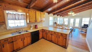 A spacious kitchen with wooden cabinets, a dishwasher, and a large island. - Welcome to Catbird Seat! (St. George Island)