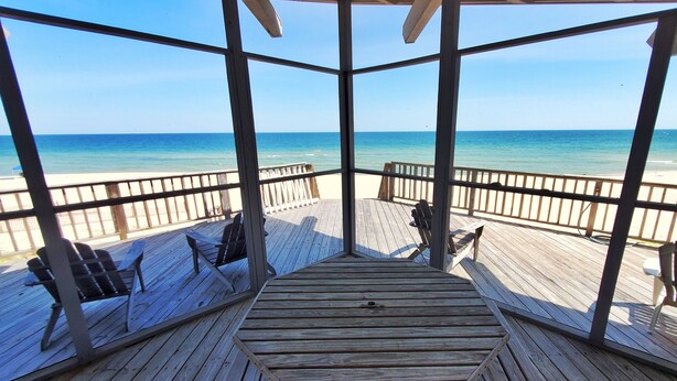 A wooden deck with chairs and a view of the ocean. - Beachfront! Screen Porch (St. George Island)