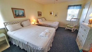 A hotel room with two beds, a small table, a chair, and a dresser. - Beachfront! Screen Porch (St. George Island)
