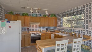 Une cuisine avec des meubles de rangement en bois, une cuisinière, un évier et une fenêtre donnant sur des arbres.