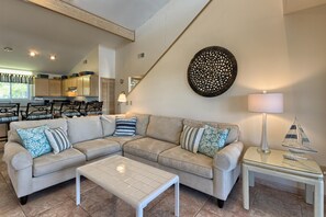 Un salon moderne avec un canapé d’angle, une table basse en verre et un coin repas comprenant des chaises et une table.