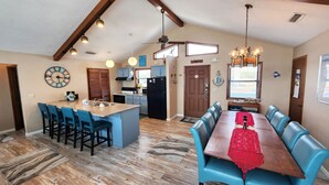 A spacious kitchen with a central island, blue bar stools, and a dining table with blue chairs. - Beachfront with large sundeck! (St. George Island)