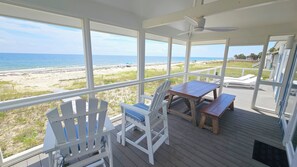 Relax in this serene beachside retreat with a wooden table and Adirondack chairs.