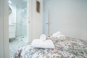 A hotel room with a bed, a shower area, and a door.