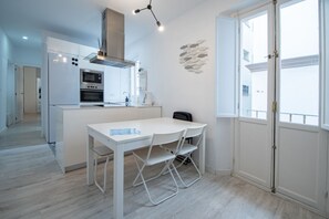 A modern kitchen with a central island, white cabinetry, and a dining area with a table and chairs.