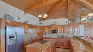 A spacious kitchen with wooden cabinets, granite countertops, stainless steel appliances, and a large island. - Welcome to Sea Knight! (St. George Island)