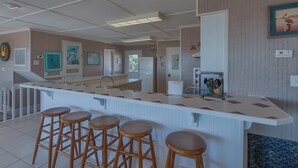Une cuisine dotée d’un îlot central, de tabourets de bar, d’un réfrigérateur et de différents éléments décoratifs sur les murs.