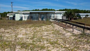 Ein Strandgrundstück mit einer Holzpromenade, die zu einer Reihe von Strandhäusern führt.