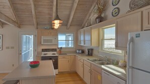 A kitchen with wooden cabinets, a microwave, a stove, a sink, and a refrigerator. - Beachfront! Large sundeck with screened in porch! (St. George Island)