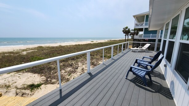 Una terraza de madera con dos sillones de relax con vista a una playa.