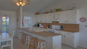 Una cocina moderna con armarios blancos, encimera de madera y una isla central con taburetes.