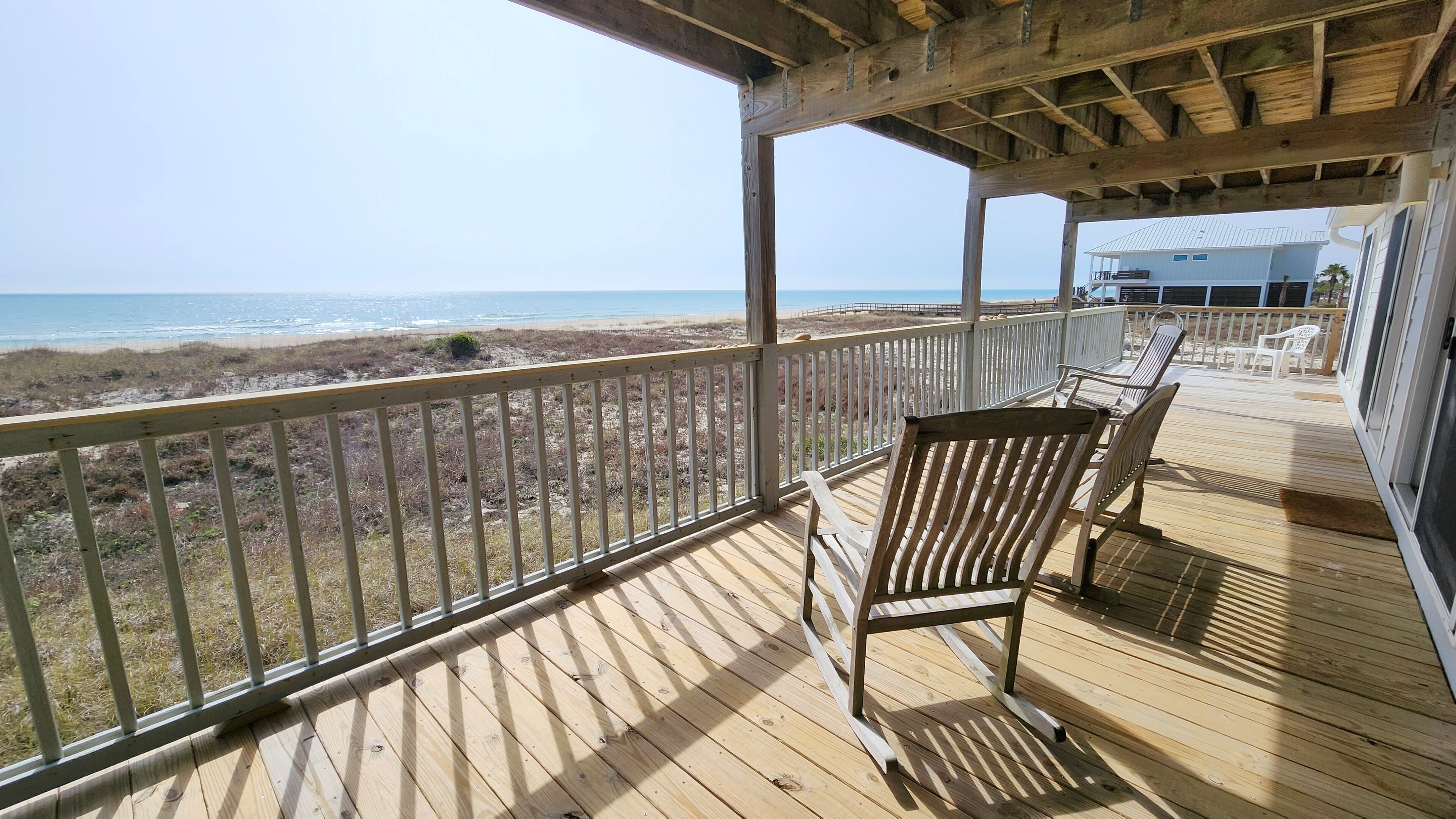 A wooden deck with a view of the beach and ocean.