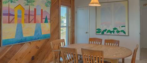 A dining area with a wooden table and chairs, a painting on the wall, and a door labeled "OWNER".