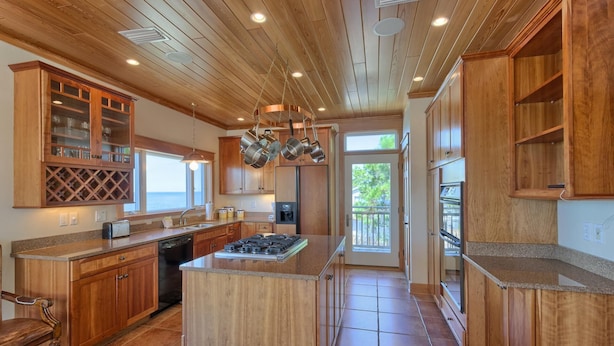 A spacious kitchen with wooden cabinets, a central island, and a view to the outside. - BAY FRONT WITH PRIVATE DOCK! HOT TUB! (St. George Island)