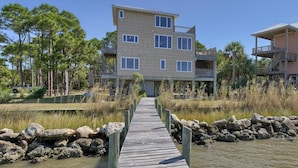 A multi-story building with a wooden deck leading to the entrance. - BAY FRONT WITH PRIVATE DOCK! HOT TUB! (St. George Island)