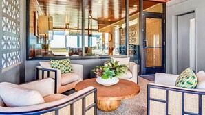 A modern interior with a round wooden coffee table, beige sofas, and a large window with a view of the street. - BEACHFRONT! PRIVATE POOL! All new renovation. (St. George Island)