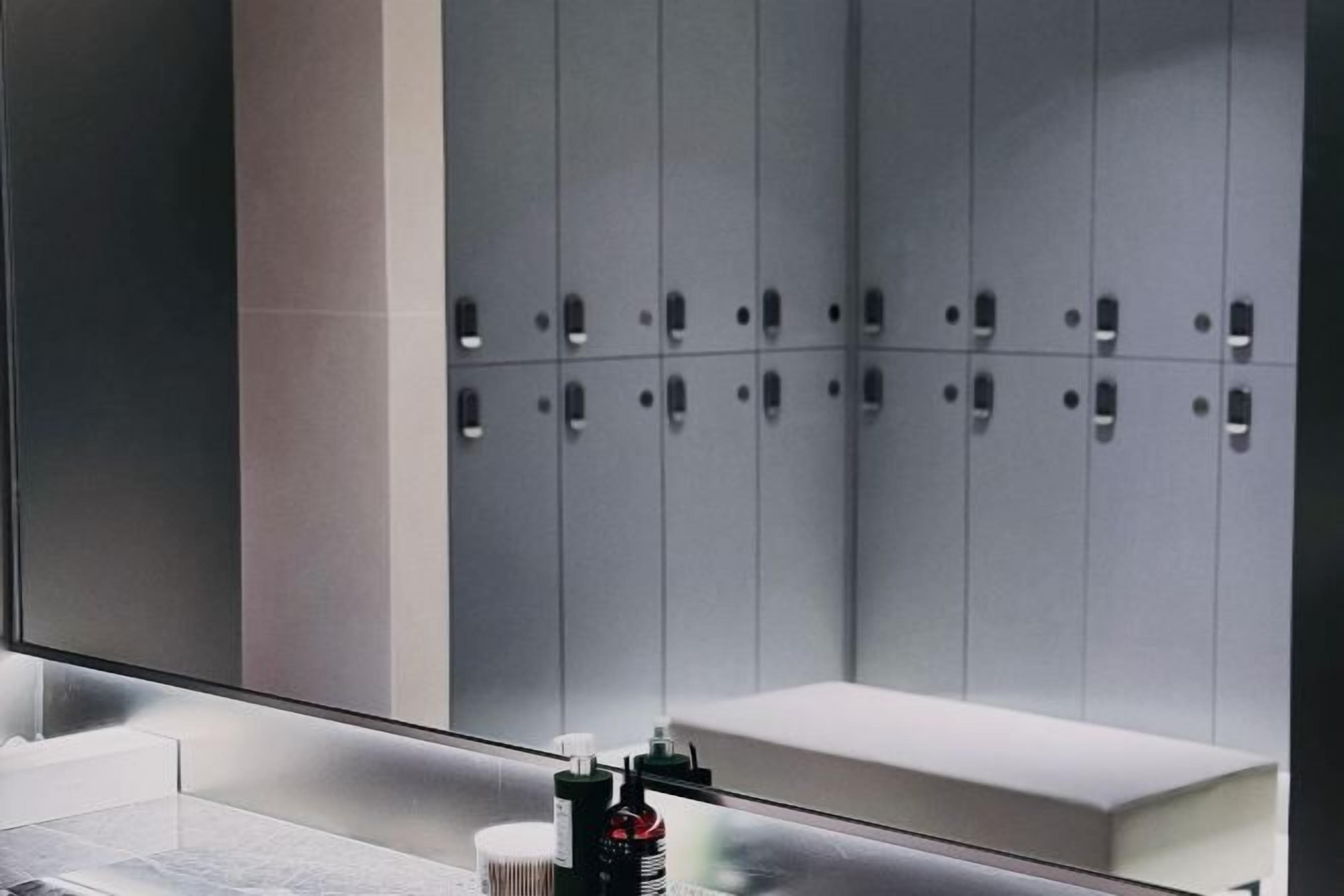A modern bathroom with a large mirror, a sink, and a bench.
