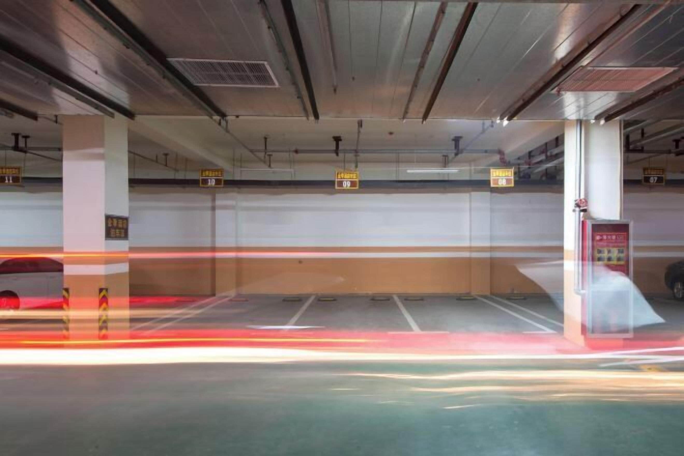 Een parkeergarage met meerdere verdiepingen, aangeduide parkeerplaatsen en een brandblusser aan de rechterkant.