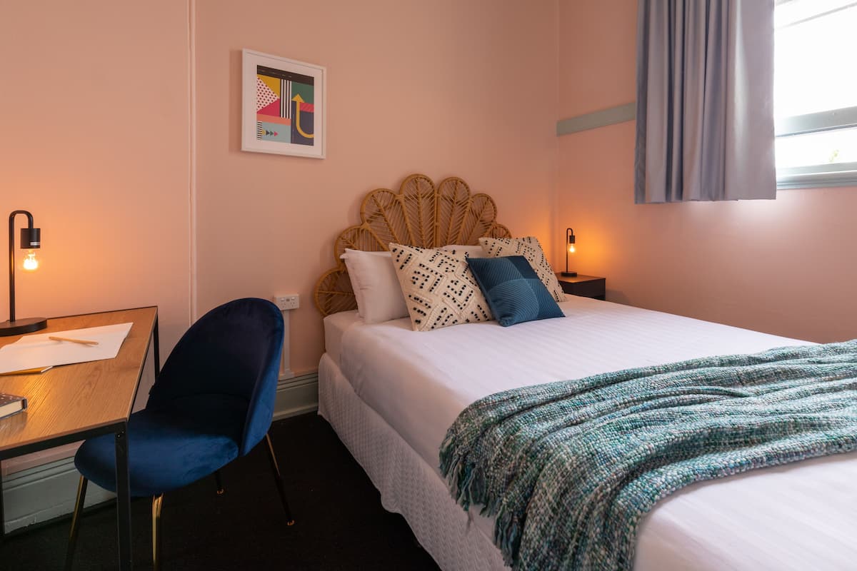 Una habitación de hotel ordenada con una cama, un escritorio y una silla.