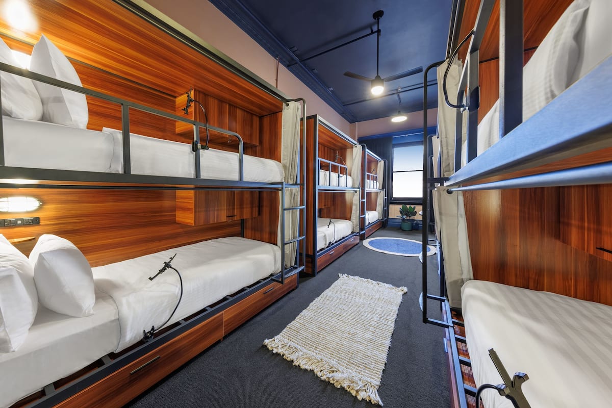 Dormitorio con literas, paneles de madera y ventilador de techo.