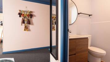 A bathroom with a toilet, sink, and mirror.