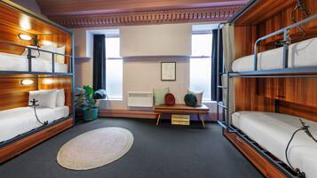 A compact room with bunk beds, a small table, and a potted plant.