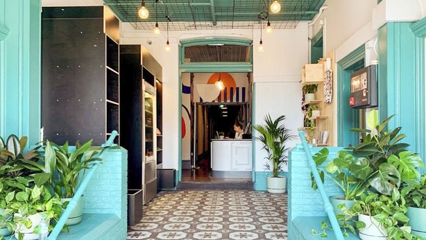 Un vestíbulo de hotel con suelo estampado, una recepción y plantas en macetas.