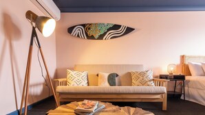Una habitación de hotel con un sofá, una mesa de centro, una lámpara y una obra de arte en la pared.