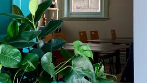 Un comedor con ventana, mesa, sillas e iluminación colgante.