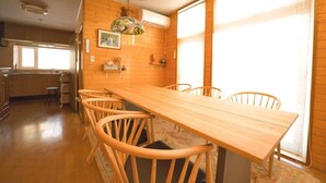 A wooden dining table with six chairs in a room with wooden walls and large windows. - SHIROKUMA NO YADO (Toyako)
