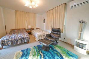 Habitación de hotel con dos camas, una silla de masaje, un calentador y un ventilador de techo.