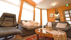 A cozy room with a leather armchair, two sofas, a wooden coffee table, and a patterned rug. - SHIROKUMA NO YADO (Toyako)