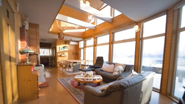 A spacious living room with a large window, a fireplace, and a cozy seating area. - SHIROKUMA NO YADO (Toyako)