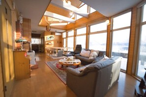 Amplia sala de estar con un gran ventanal, chimenea y un rincón de descanso acogedor.