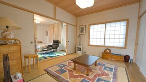 A traditional Japanese-style room with tatami flooring, a low table, a chair, and a futon bed. - SHIROKUMA NO YADO (Toyako)