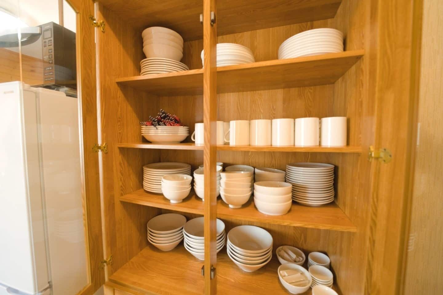 Un mueble de madera con varios estantes que contiene cuencos, platos y tazas.