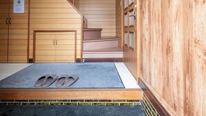 Habitación de hotel con paneles de madera, una escalera, una puerta con un letrero que dice 'Solo Personal' y un felpudo con pantuflas.