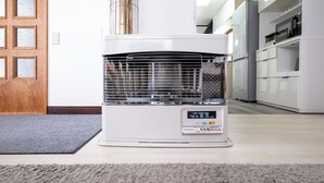 Un acondicionador de aire blanco en una cocina moderna con puerta de madera y armarios blancos.
