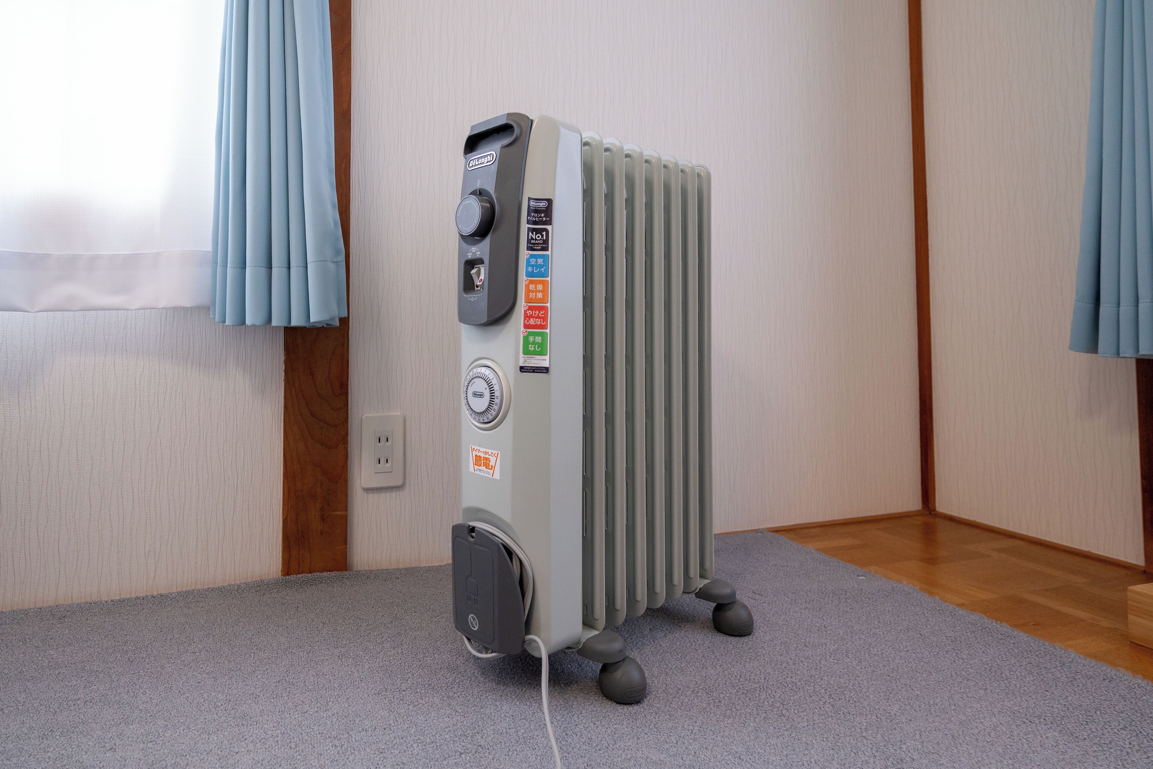A radiator with control knobs and a power outlet on the wall.