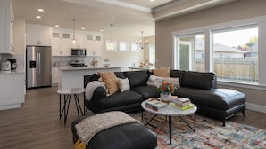 A modern kitchen with white cabinets, stainless steel appliances, and pendant lighting.
