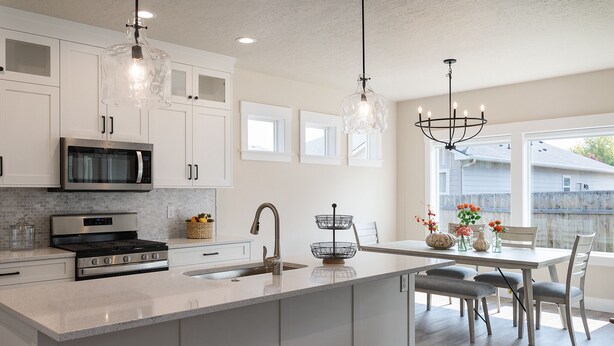 A modern kitchen with white cabinetry, stainless steel appliances, and a large island with a sink.